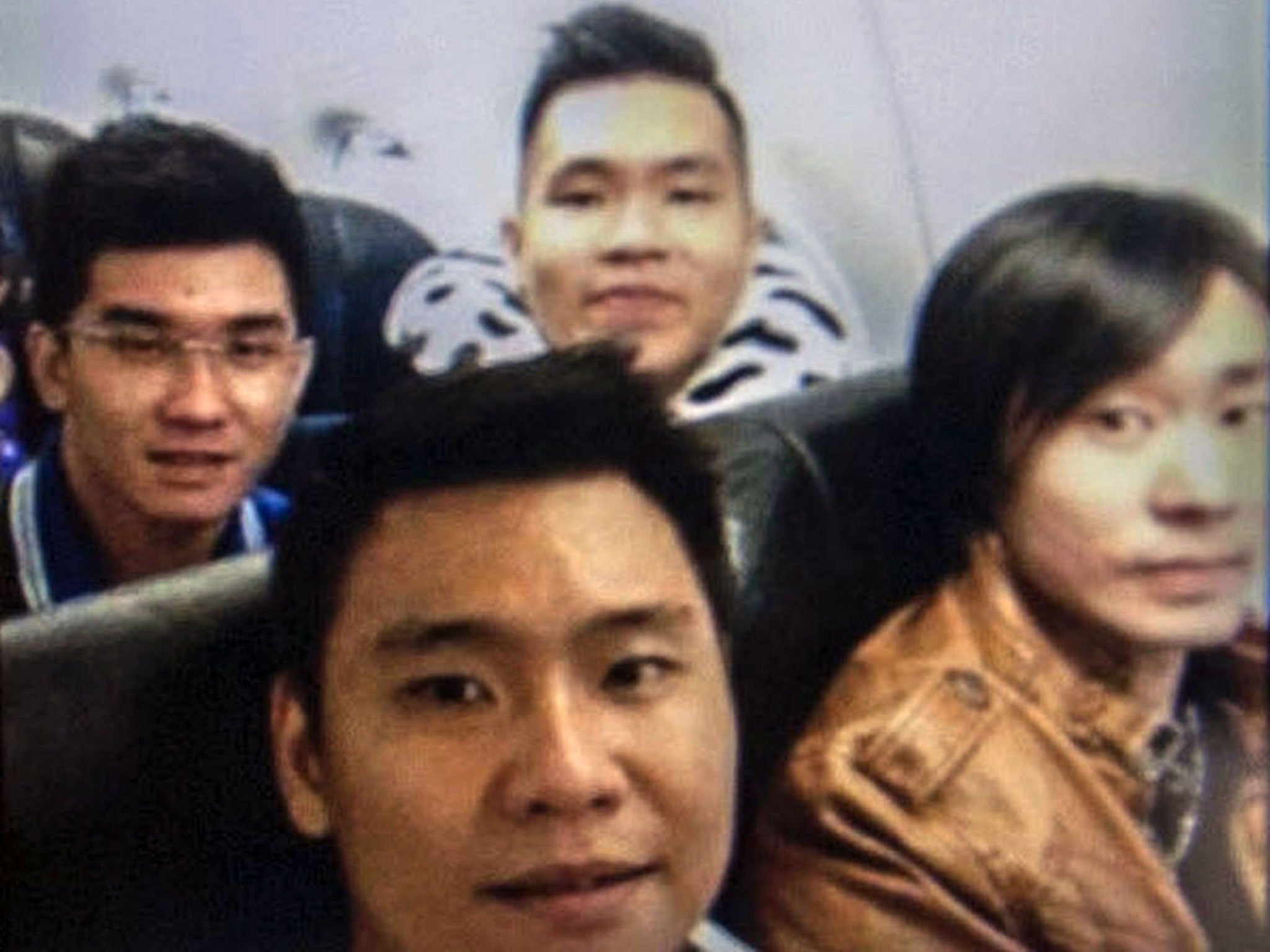 A picture on a mobile phone shows Hendra Gunawan Sawal (back C in the photograph), sitting onboard AirAsia flight QZ8501 before it went missing in the Java sea, as his family holds a prayer ceremony for him in Surabaya