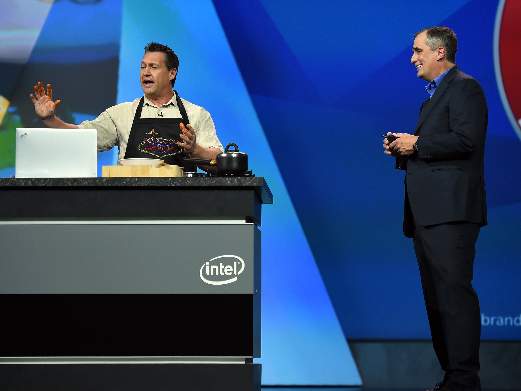 Intel CEO Brian Krzanich (R) watches a chef demonstrate a cooking application using Intel's RealSense technology that uses voice and gesture commands to eliminate the need to touch a device with dirty hands in the kitchen