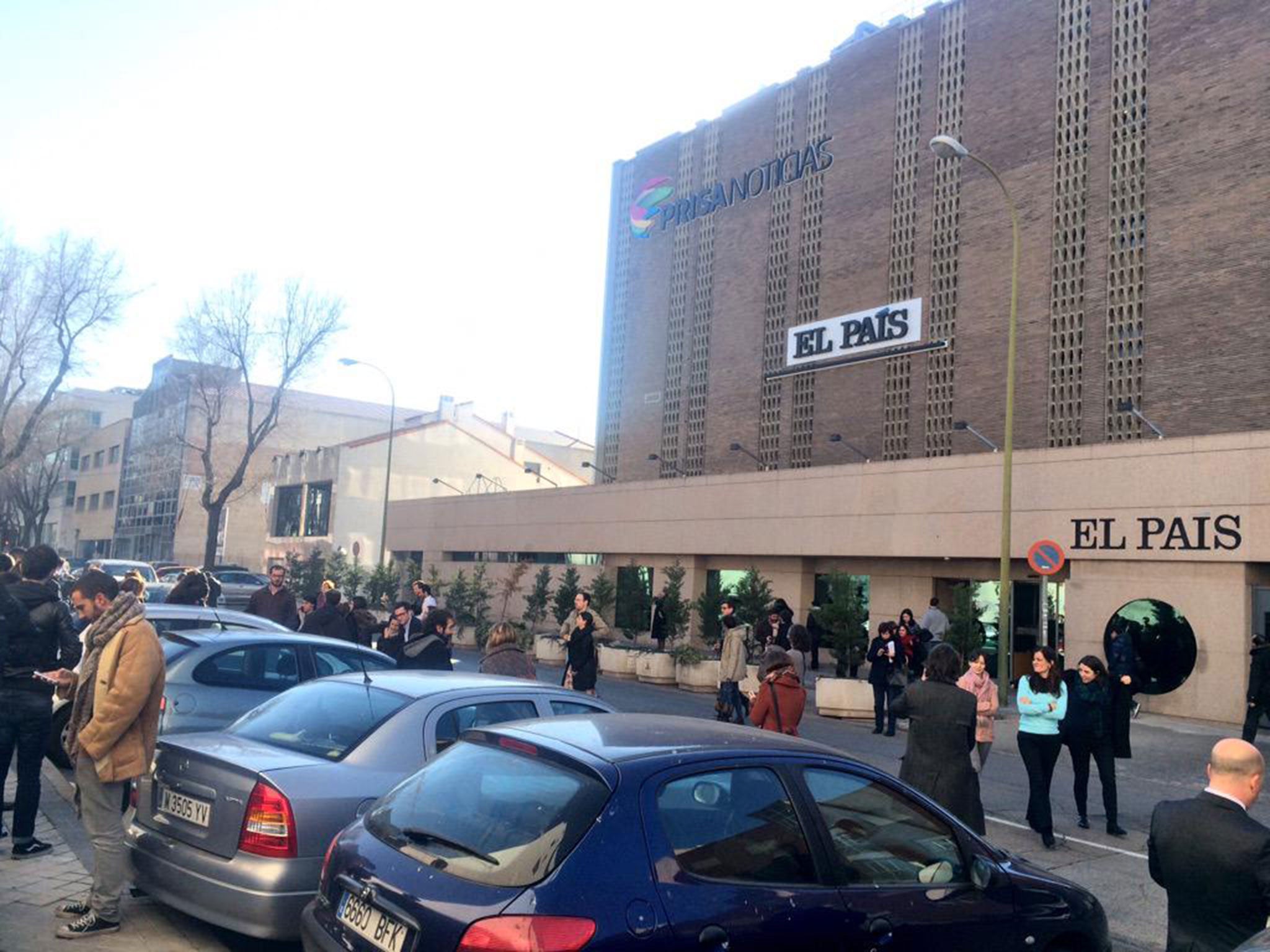 Prisa employees wait outside their office building after it was evacuated due to a suspicious package