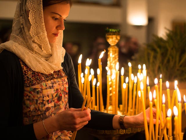 A member of the congregartion lights a candle during a midnight mass vigil at the Russian Orthodox Church Abroad's 'Cathedral of the Dormition of the Mother of God and the Royal Martyrs' Church in London