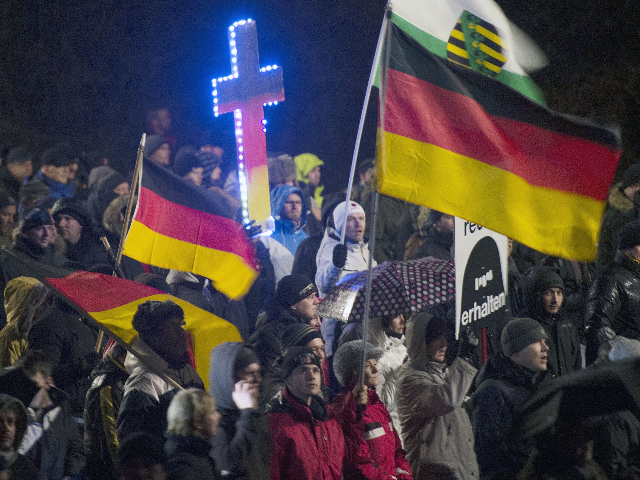 A demonstrator holds a crucifix (C) in the colors of Germany during a rally by a mounting right-wing populist movement called Pegida in Dresden