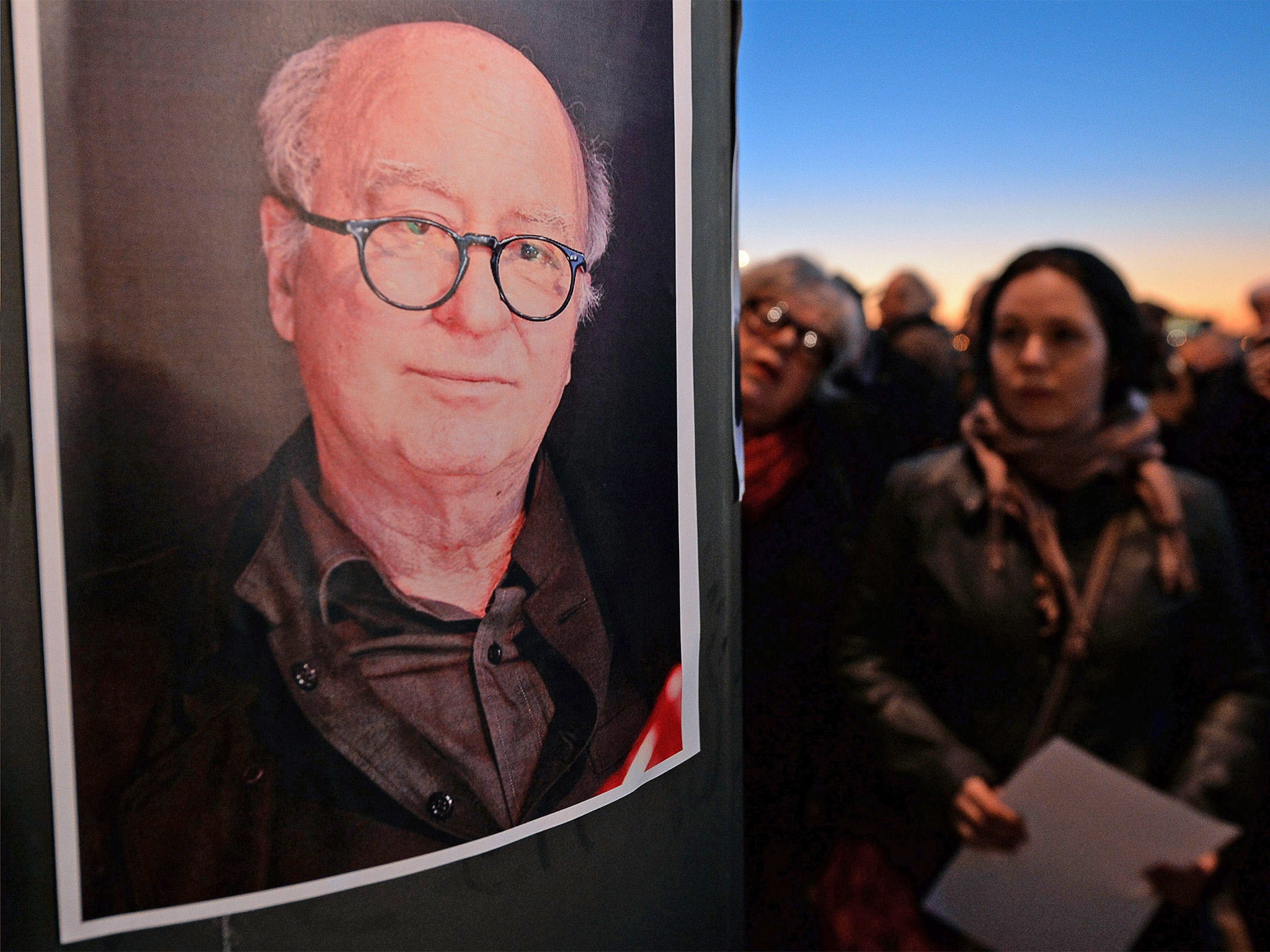 People stand stand in Marseille, southern France, next to a portrait of French cartoonist Georges Wolinksi, killed during an attack by unknown gunmen on the offices of the satirical weekly, 'Charlie Hebdo'