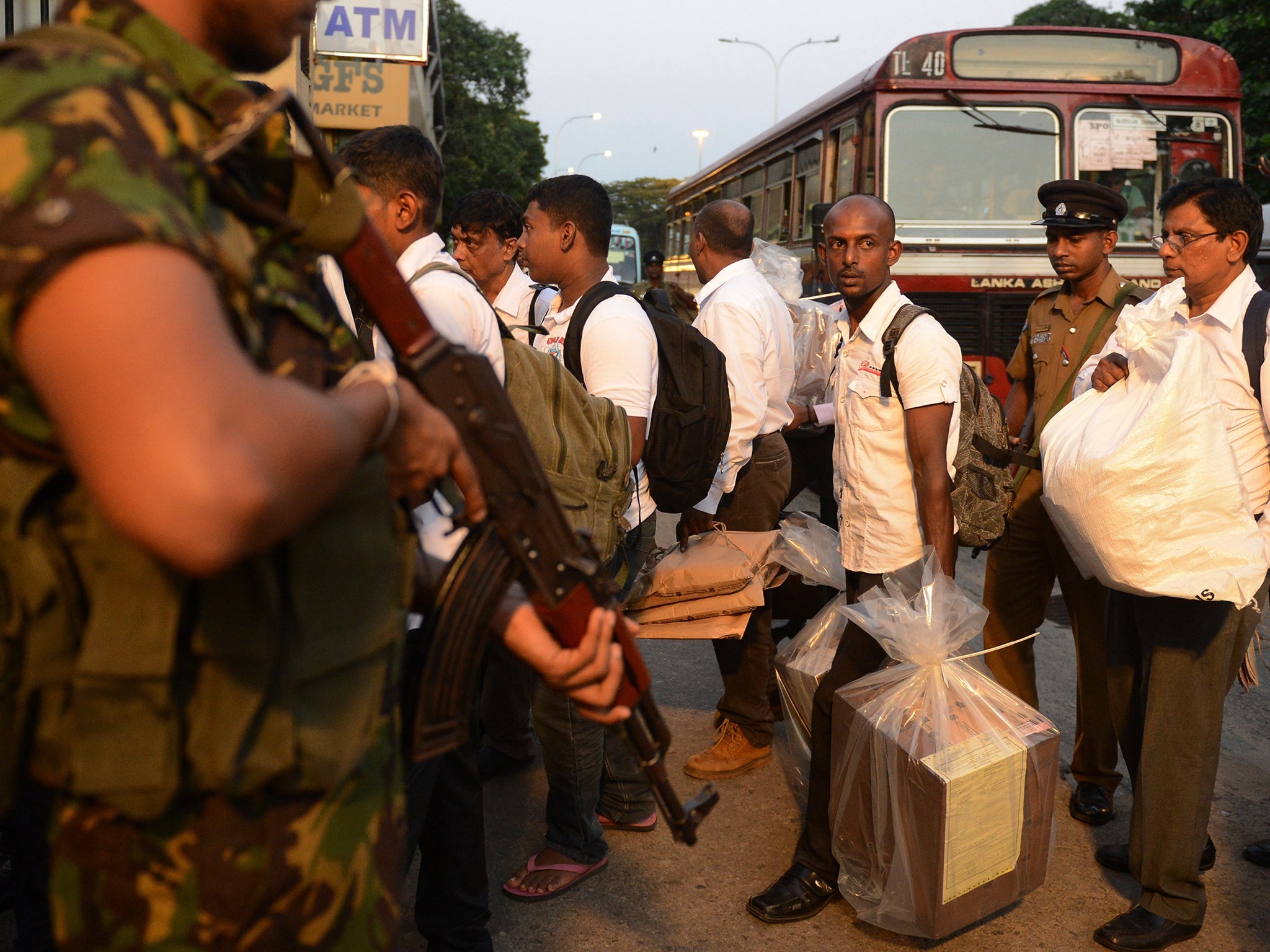 Sri Lankan election officials carry ballot boxes to be transferred to a main counting centre