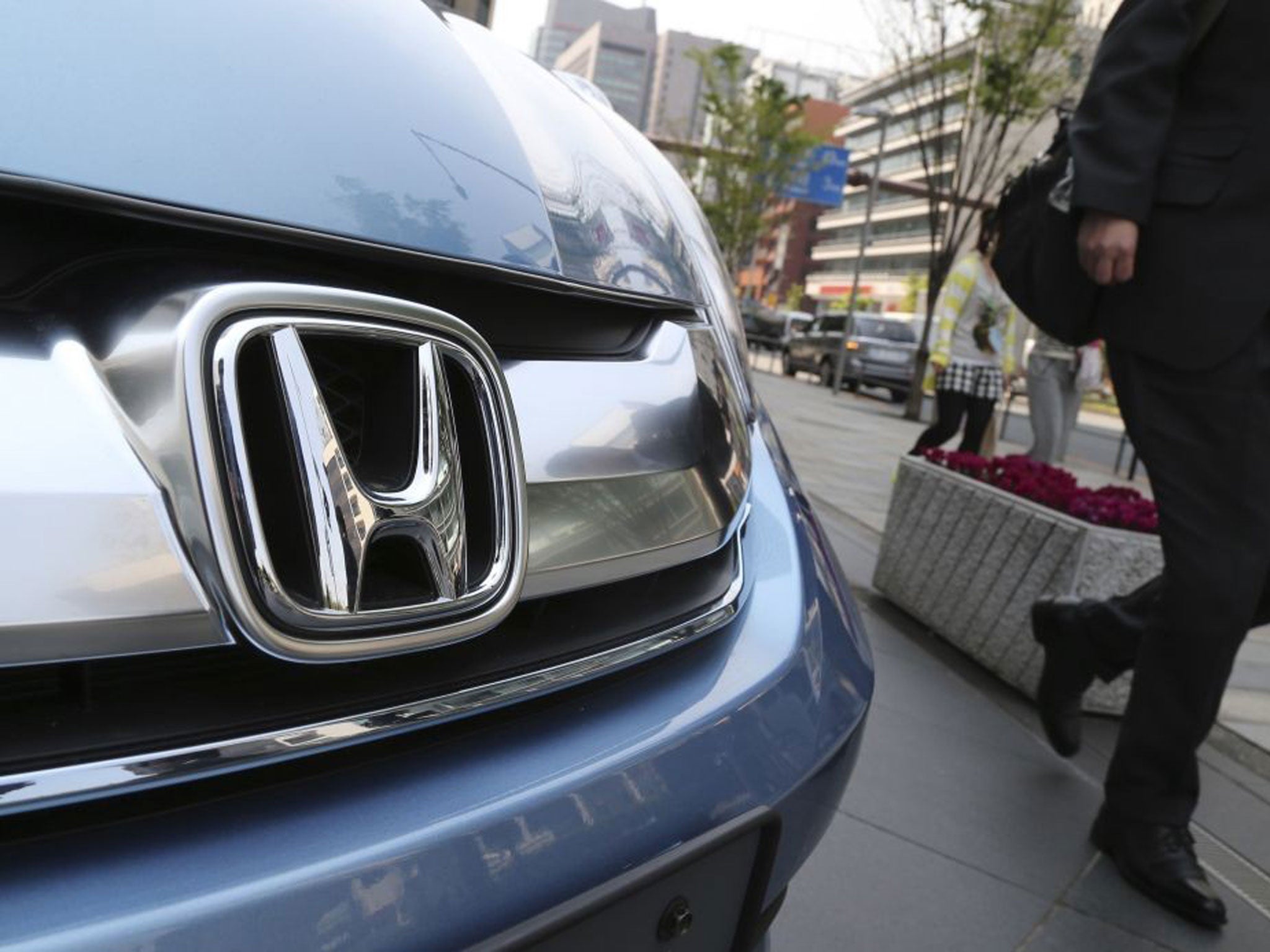 A man walks past a Honda on display at Honda Motor Co. headquarters in Tokyo