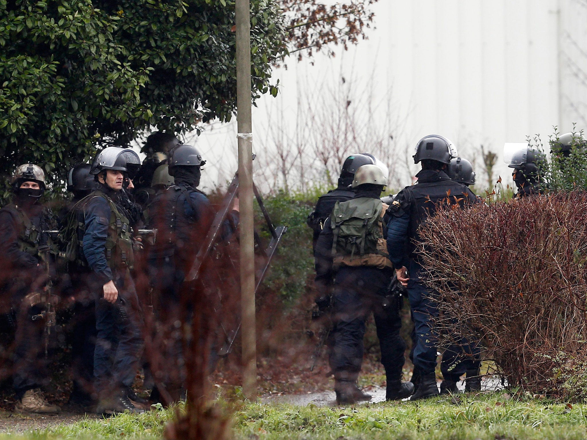 Police officers gather in an industrial area where the suspects are reportedly