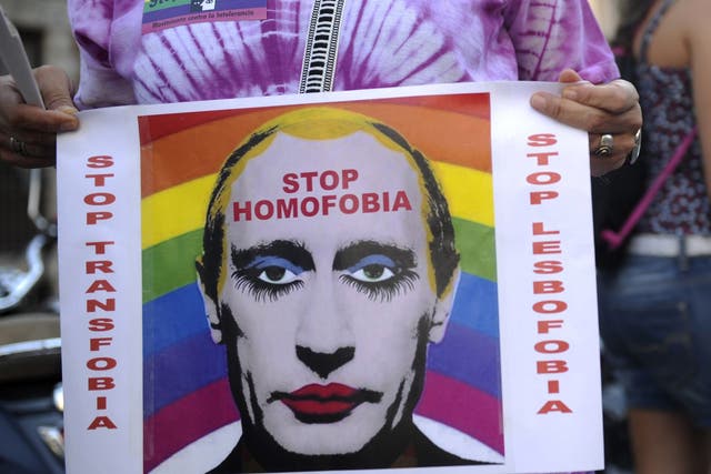 A demonstrator holds a poster depicting Russian President Vladimir Putin with make-up as he protests against homophobia