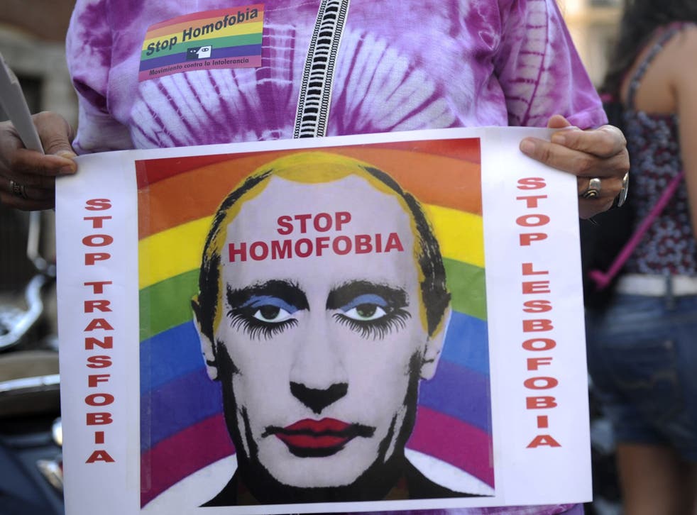 A demonstrator holds a poster depicting Russian President Vladimir Putin with make-up as he protests against homophobia