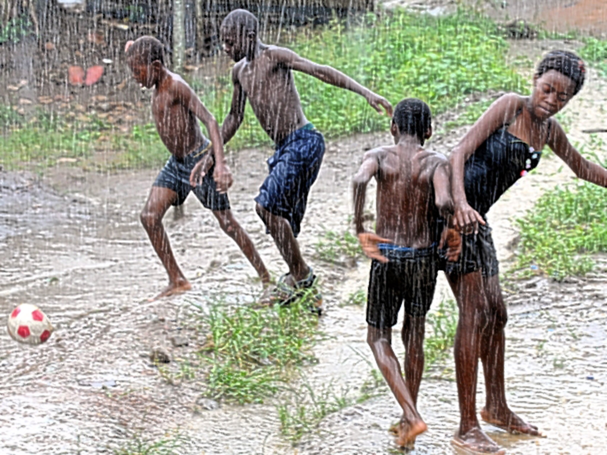 Children play football in the rain in Bata