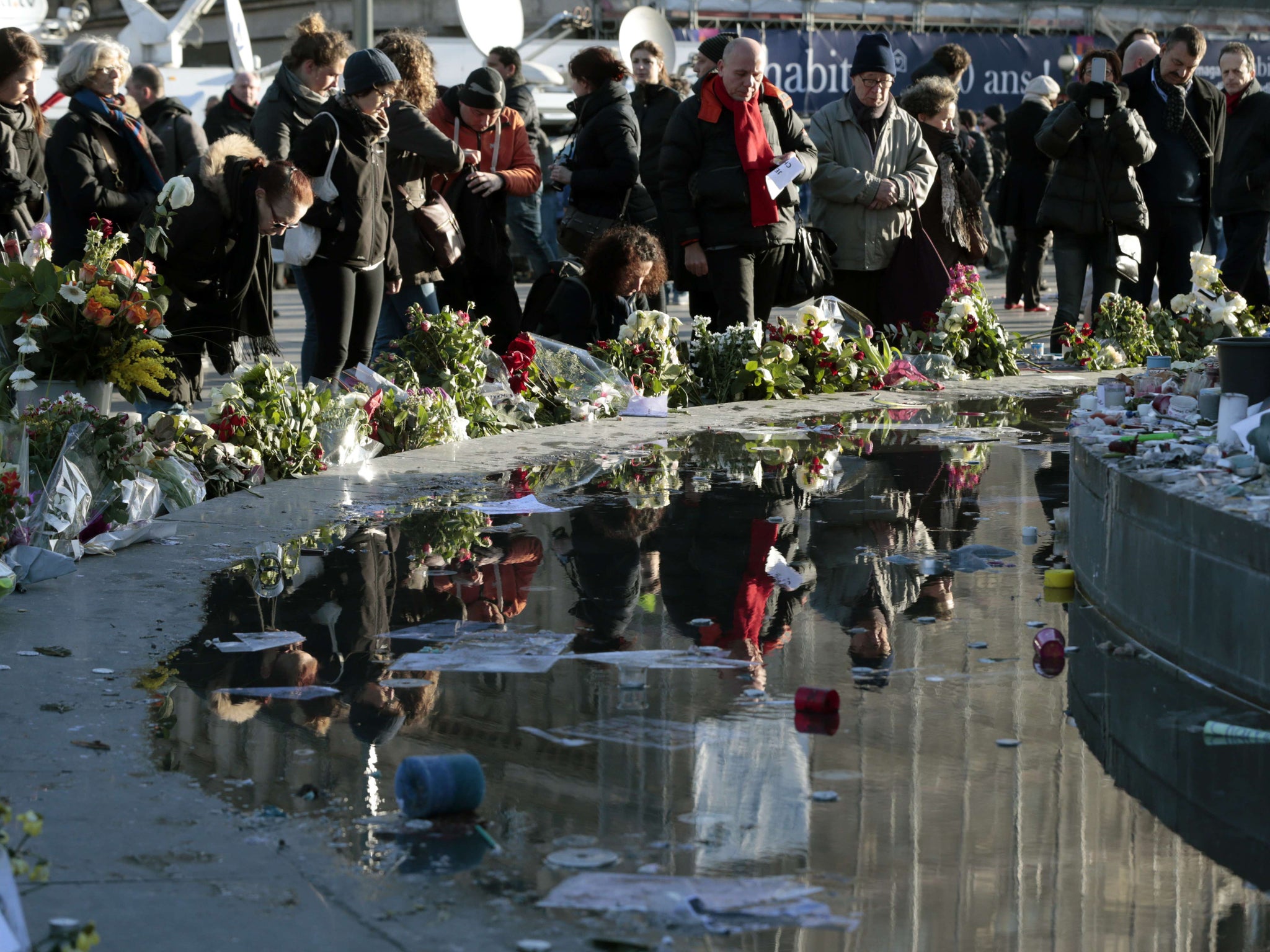 People gather at the foot of the centrepiece of Place de la Republique, a statue of Marianne, in east Paris prior to the march expected to draw thousands