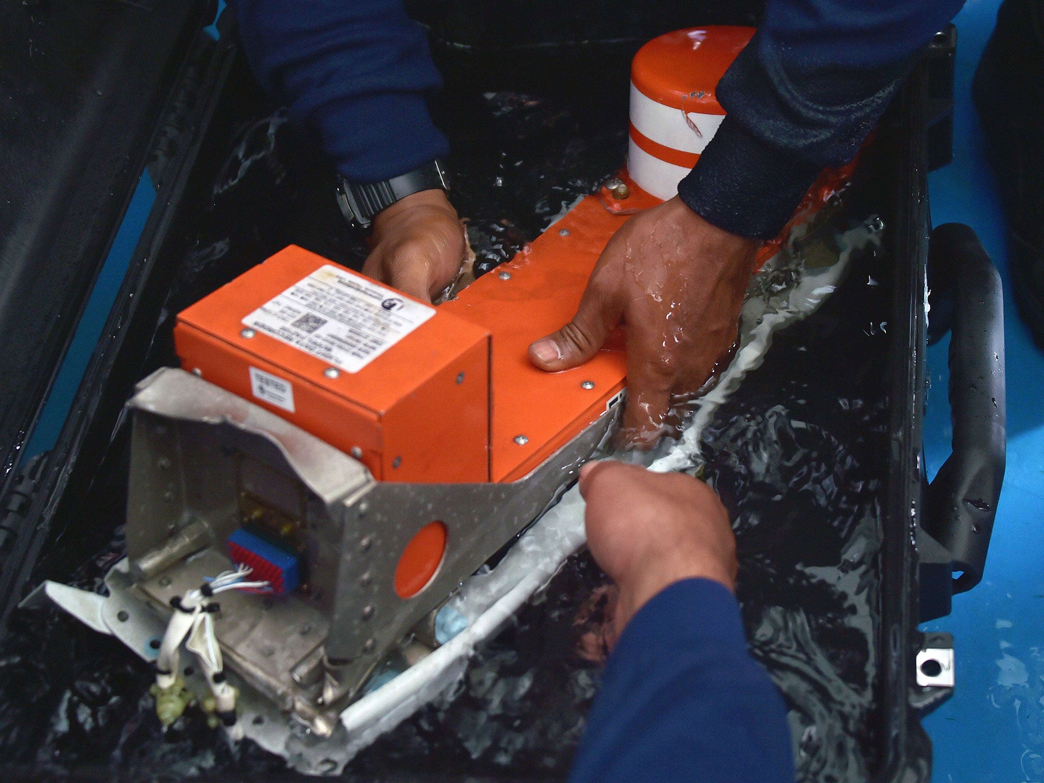 Indonesian divers handle the FDR (Flight Data Recorder) of the AirAsia flight QZ8501 after it was retrieved from the Java Sea on January 12, 2015