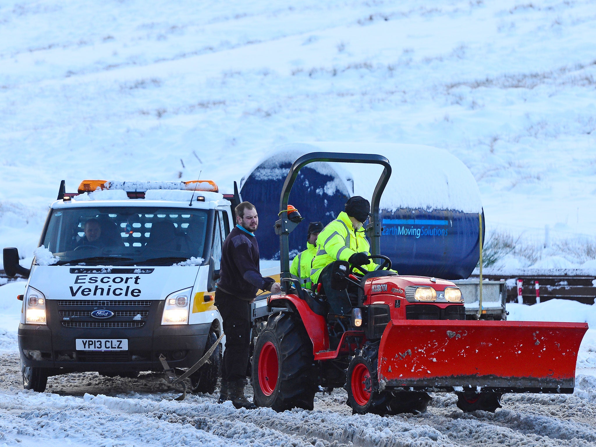 A workman with a small tractor helps to pull a van out of the deep snow in Tyndrum, Stirlingshire