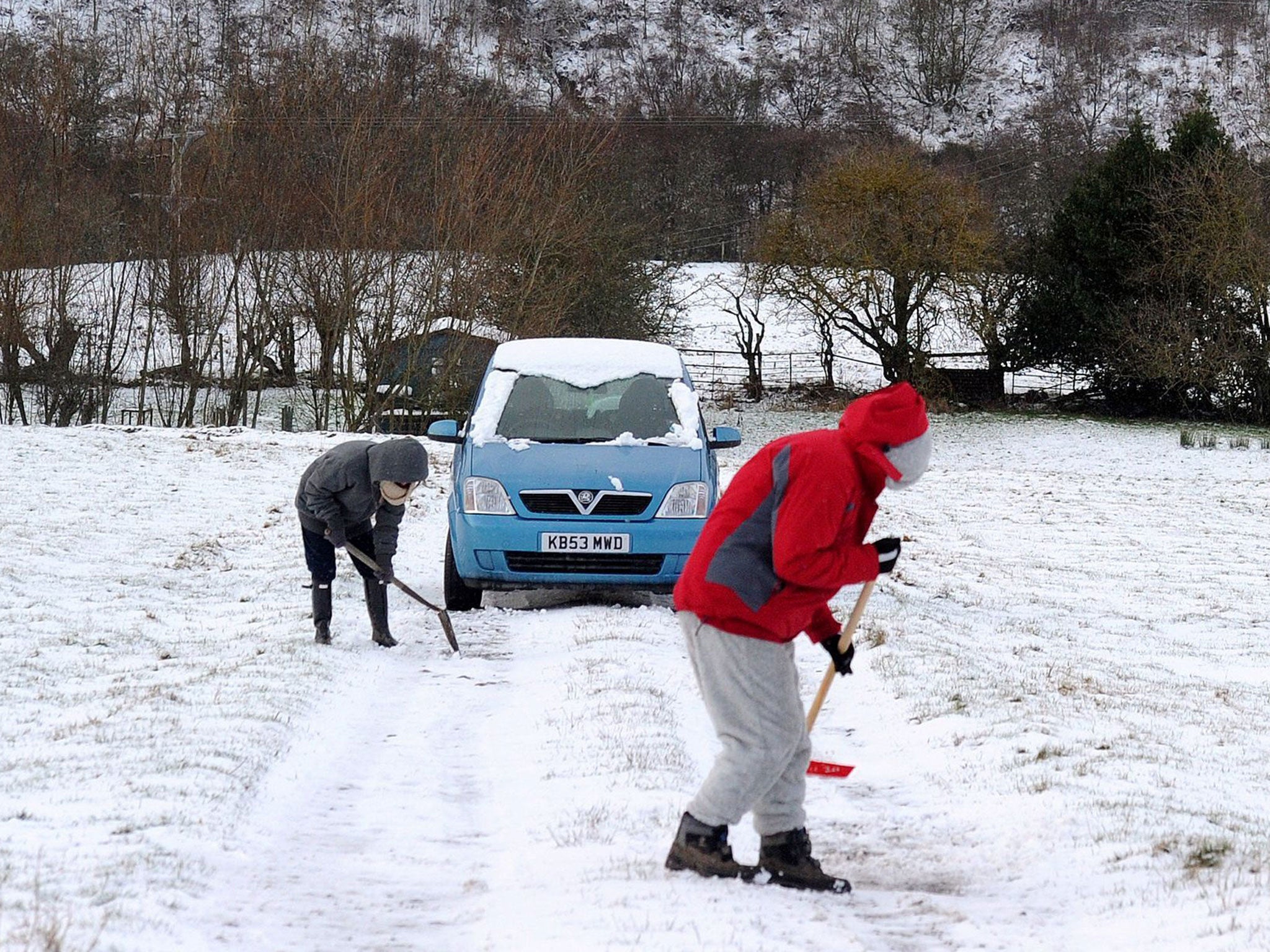 People clear the snow from the road in Allendale, Northumberland, as more winter weather swept across the UK bringing disruption to rush-hour traffic