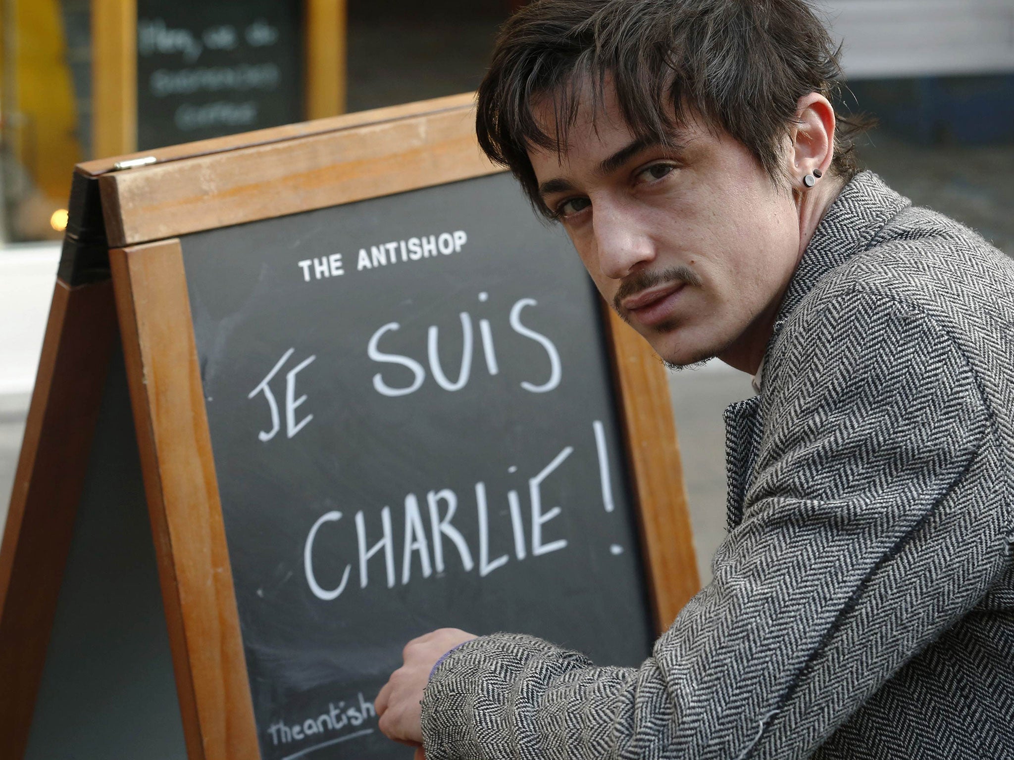 Adel Defilaux, a French-born Muslim, poses with his advertising board on which he has written "Je Suis Charlie!" outside his cafe in Brick Lane