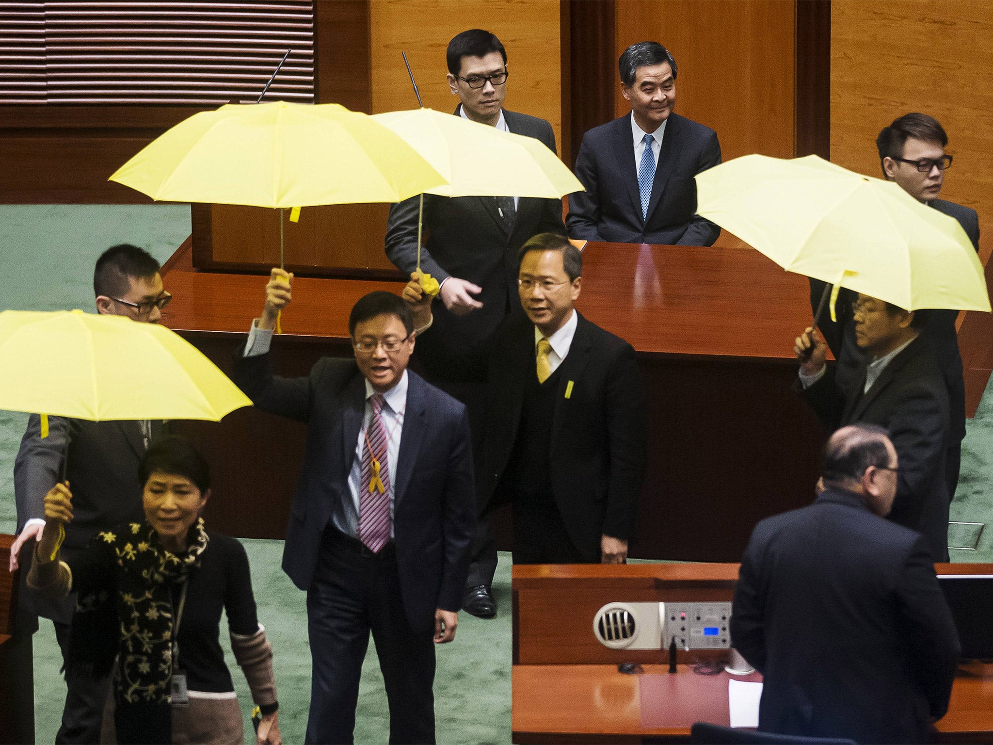 Pro-democracy lawmakers brandish yellow umbrellas, the symbol of the Occupy Central movement, as Chun-ying (blue tie) delivers his address