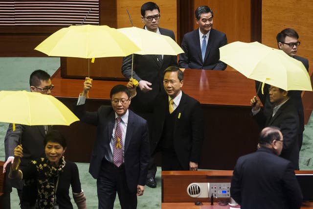 Pro-democracy lawmakers brandish yellow umbrellas, the symbol of the Occupy Central movement, as Chun-ying (blue tie) delivers his address