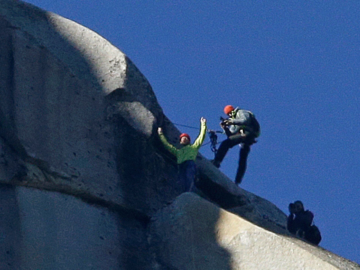 Tommy Caldwell, top, raises his arms after reaching the summit of El Capitan, Wednesday, Jan. 14, 2015, as seen from the valley floor in Yosemite National Park, Calif.