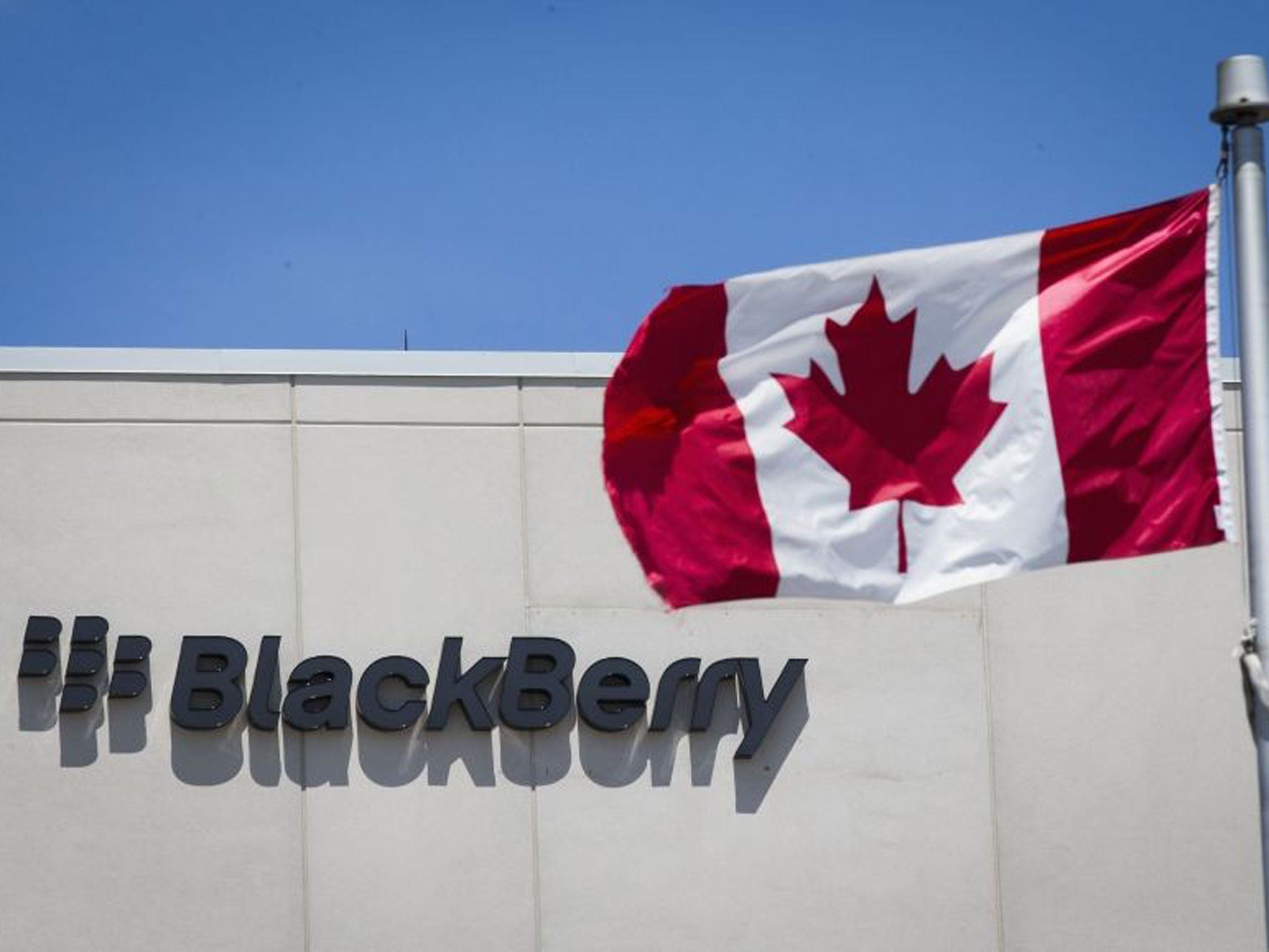A Canadian flag is pictured in front of a Blackberry sign in Waterloo, Ontario