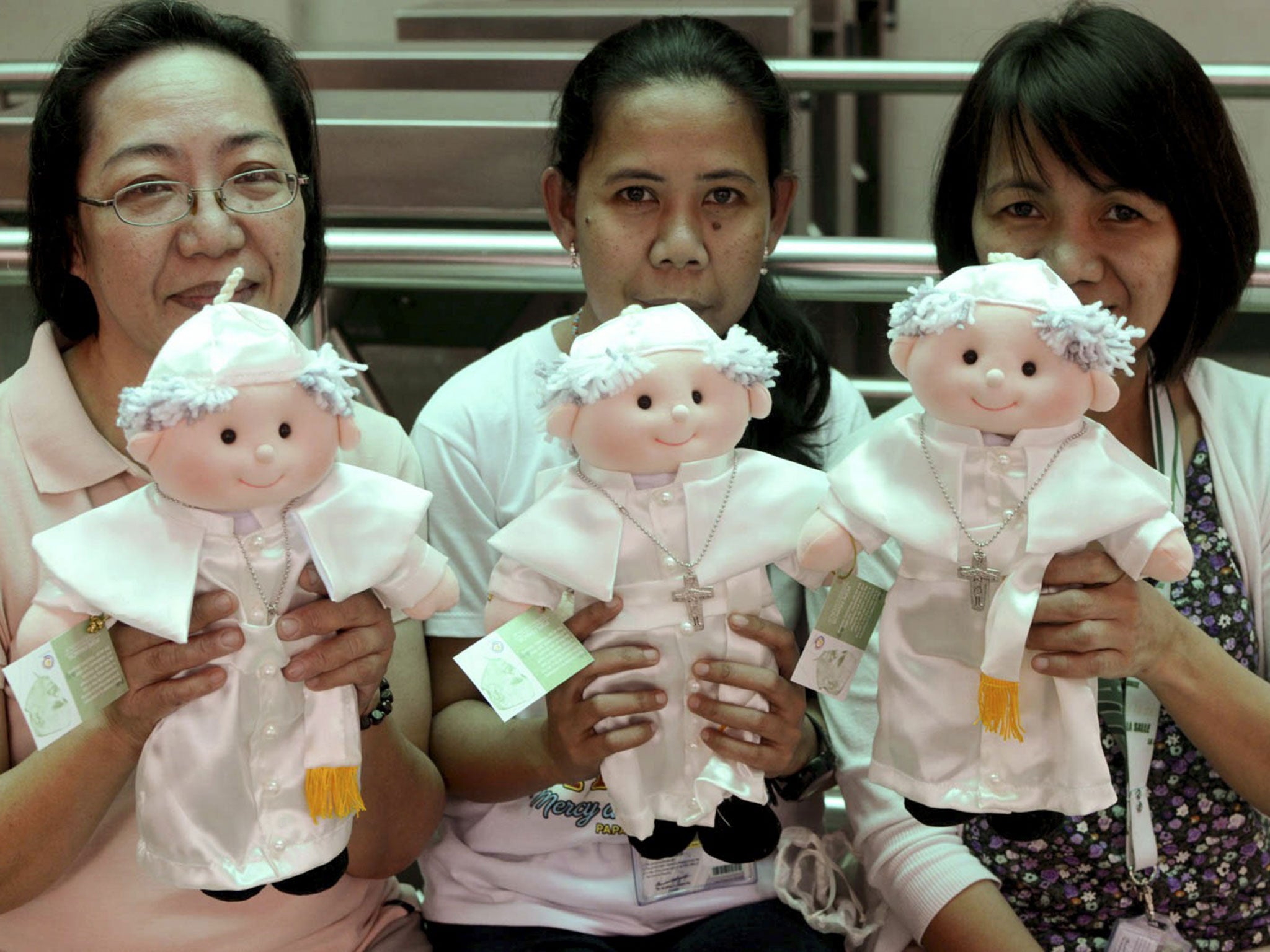 Filipino devotees hold limited edition Pope Francis dolls that are sold by the De La Salle University in Manila, Philippines Wednesday, Jan. 14, 2015