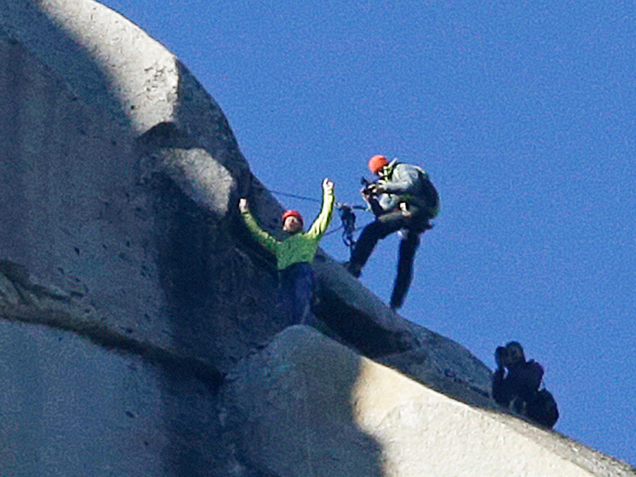 Tommy Caldwell, top, raises his arms after reaching the summit of El Capitan