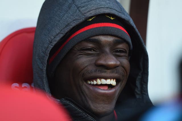 Mario Balotelli laughs on the Liverpool bench