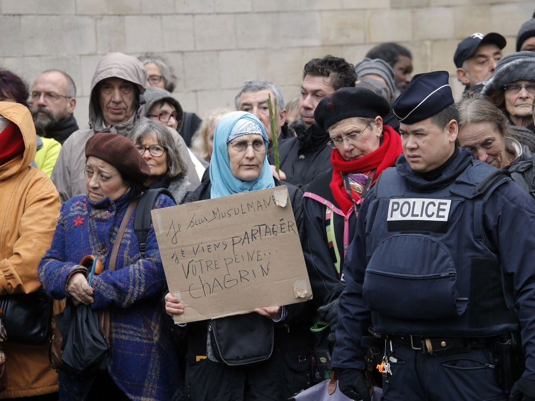 A woman holds a board reading: "I am Muslim, I am here to share your pain" outside Pere Lachaise cemetery during Tignous' funeral (AP)