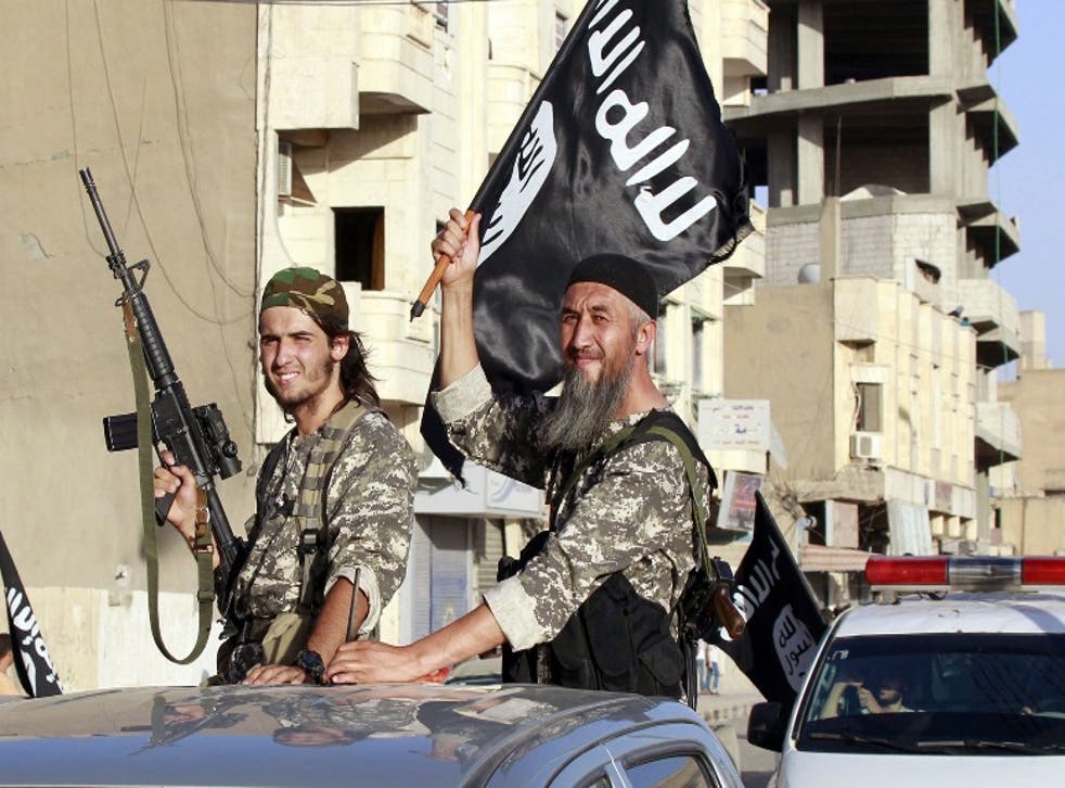 Isis fighters wave flags as they take part in a military parade along the streets of Syria's northern Raqqa province