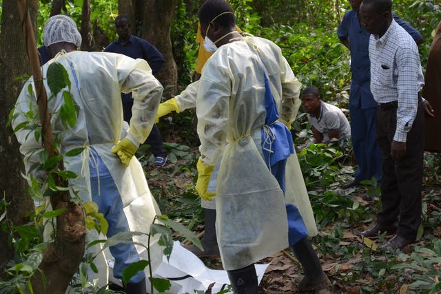 Red cross workers prepare to bury a victim of Ebola. Schools in Liberia will reopen in February