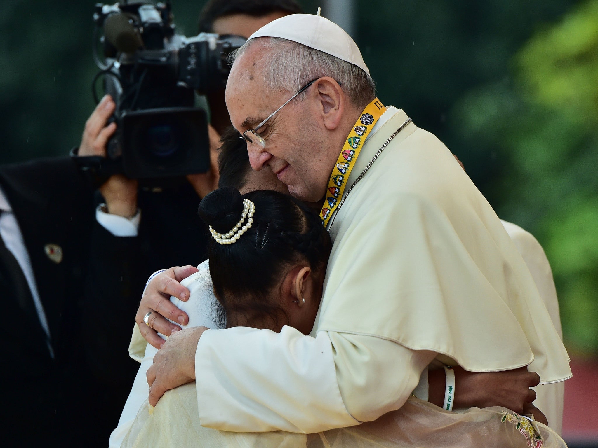 Pope Francis (R) embraces two children, including 12-year-old Glyzelle Palomar (2nd R), during his visit to the University of Santo Tomas in Manila