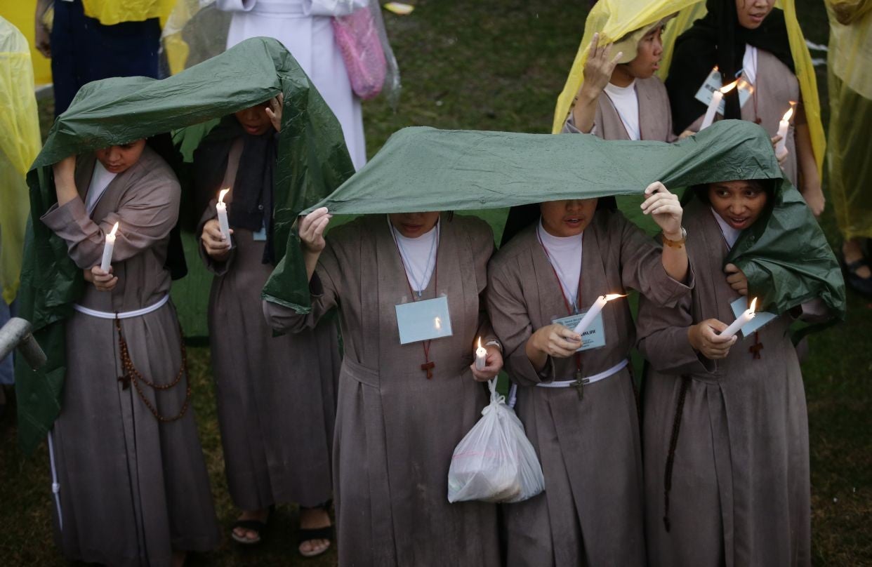 Groups of nuns shelter themselves from the downpour