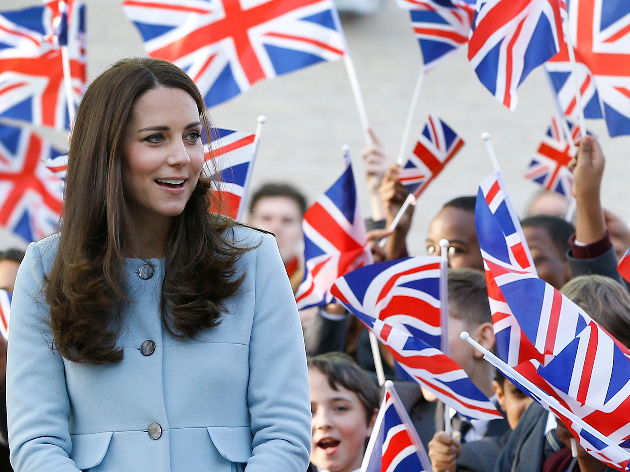 Britain's Kate, the Duchess of Cambridge walks past pupils with flags during a visit to formally open Kensington Aldridge Academy in London
