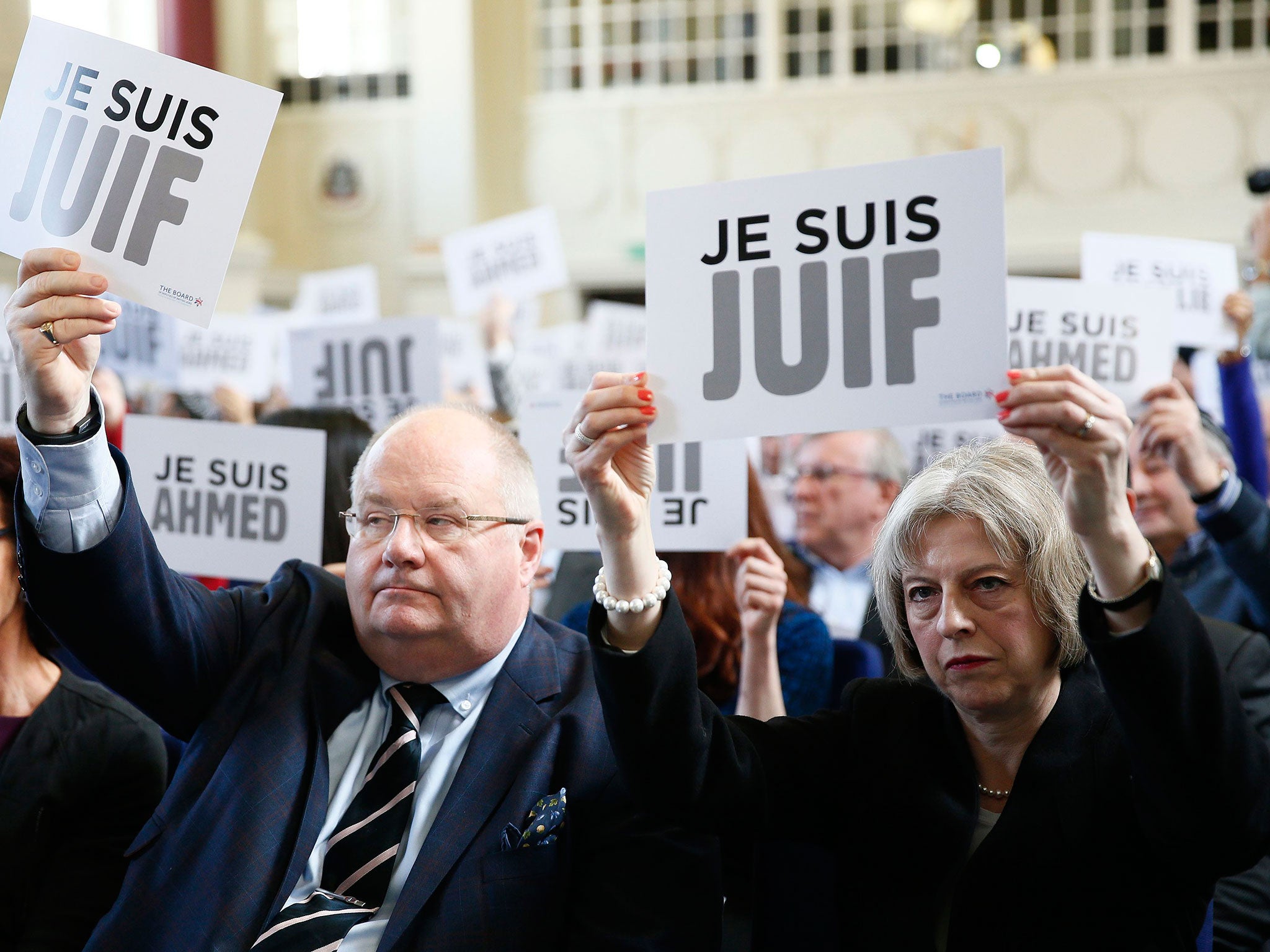 Britain's Secretary of State for Communities Eric Pickles and Home Secretary Theresa May hold up signs reading "I am Jewish" during a Board of Deputies of British Jews event in London
