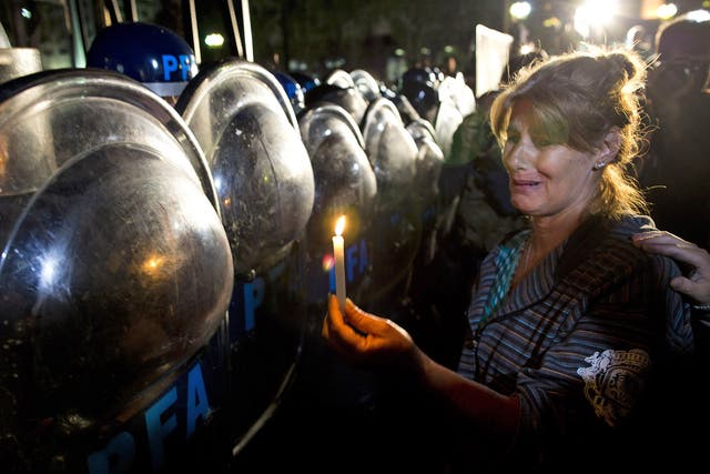 A protester holds a candle up to riot police during a vigil for Alberto Nisman, in Plaza de Mayo in Buenos Aires