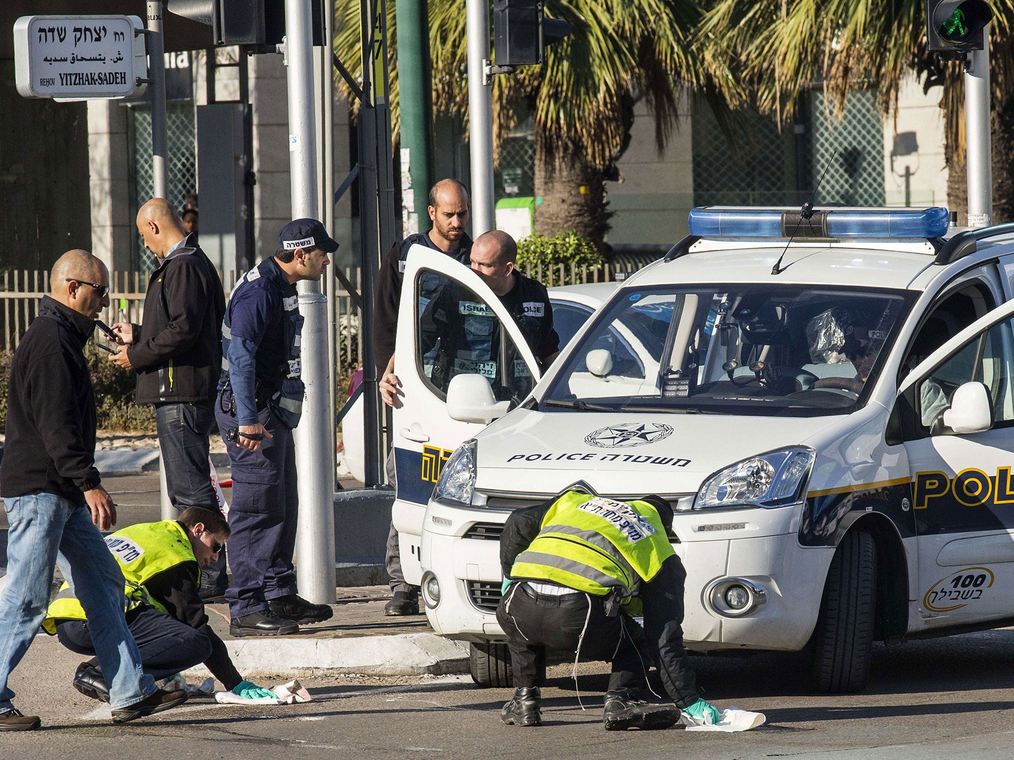 Israeli emergency services personnel clean the sidewalk at the scene of an attack