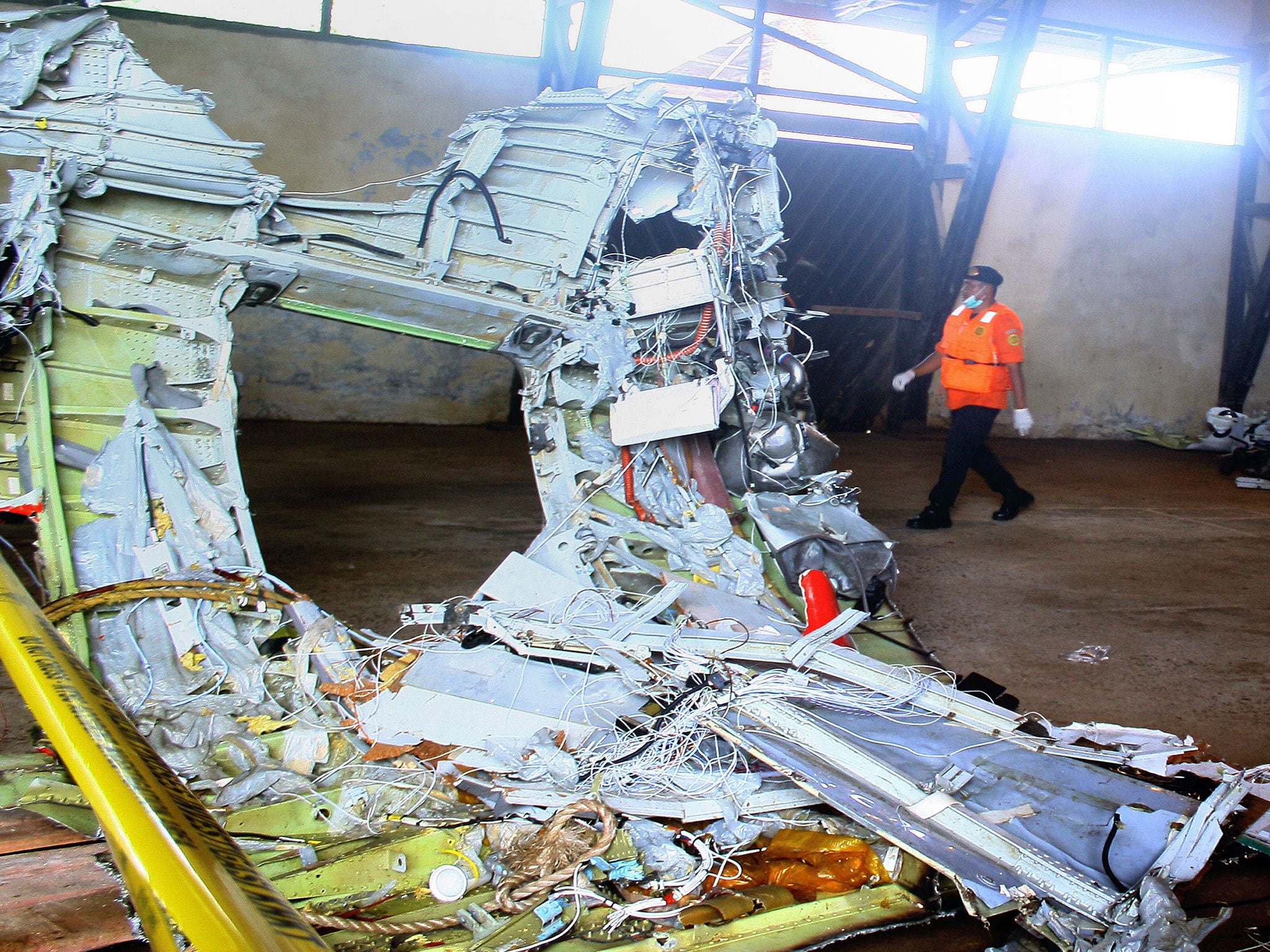 A member of Indonesia's search and rescue team walks past wreckage of AirAsia flight QZ8501 recovered at sea and stored in a warehouse for investigators in Kumai, Central Kalimantan on Borneo island