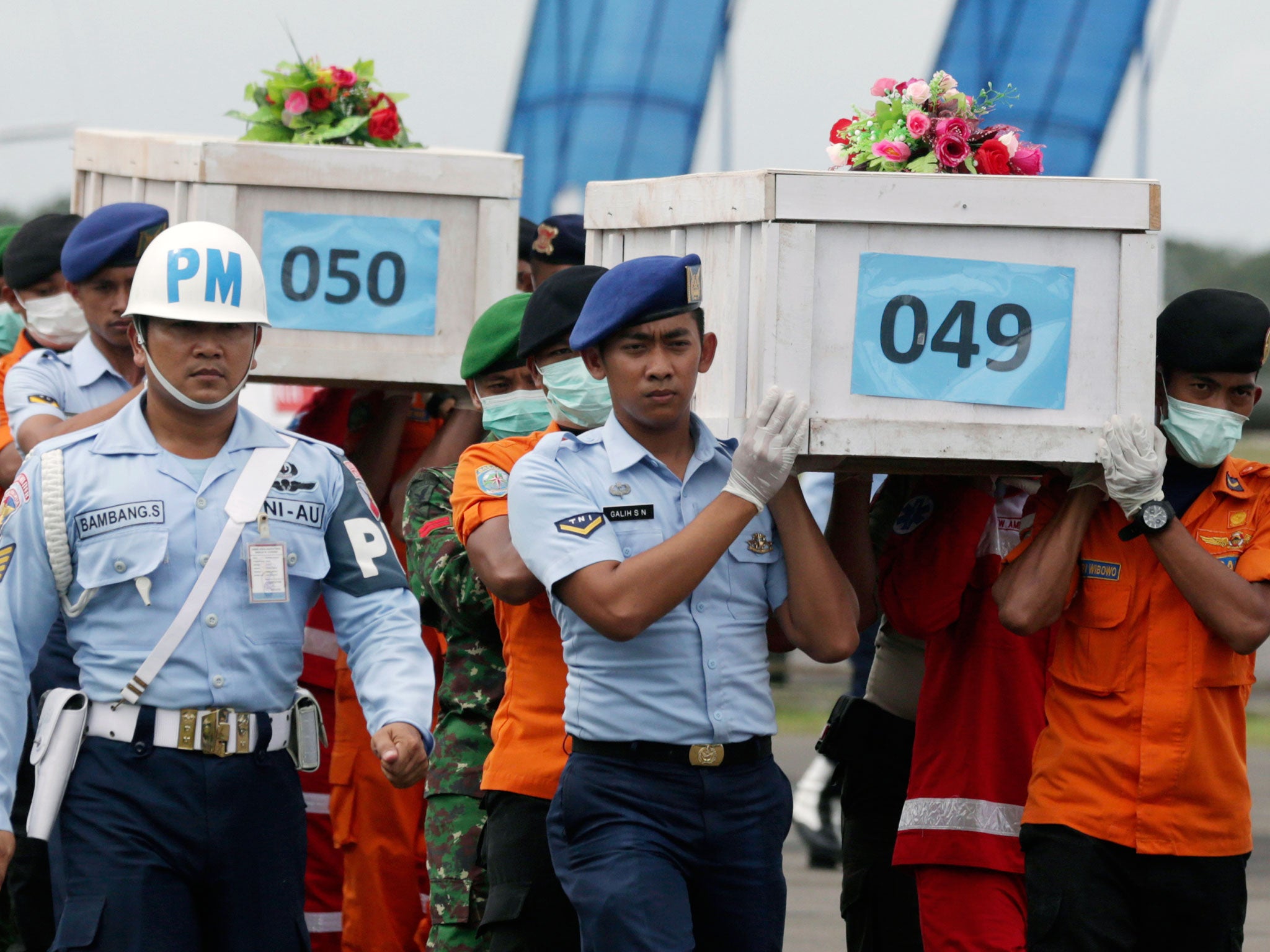 Members of the National Search and Rescue Agency carry coffins containing bodies of the victims aboard AirAsia Flight 8501