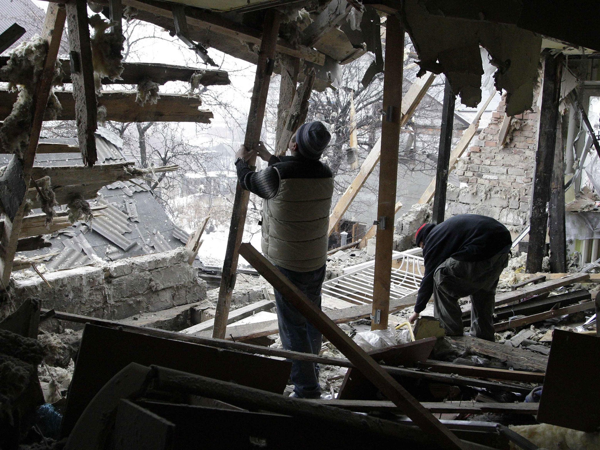 Local residents remove debris at a house damaged by recent shelling in Donetsk, eastern Ukraine, on January 21, 2015