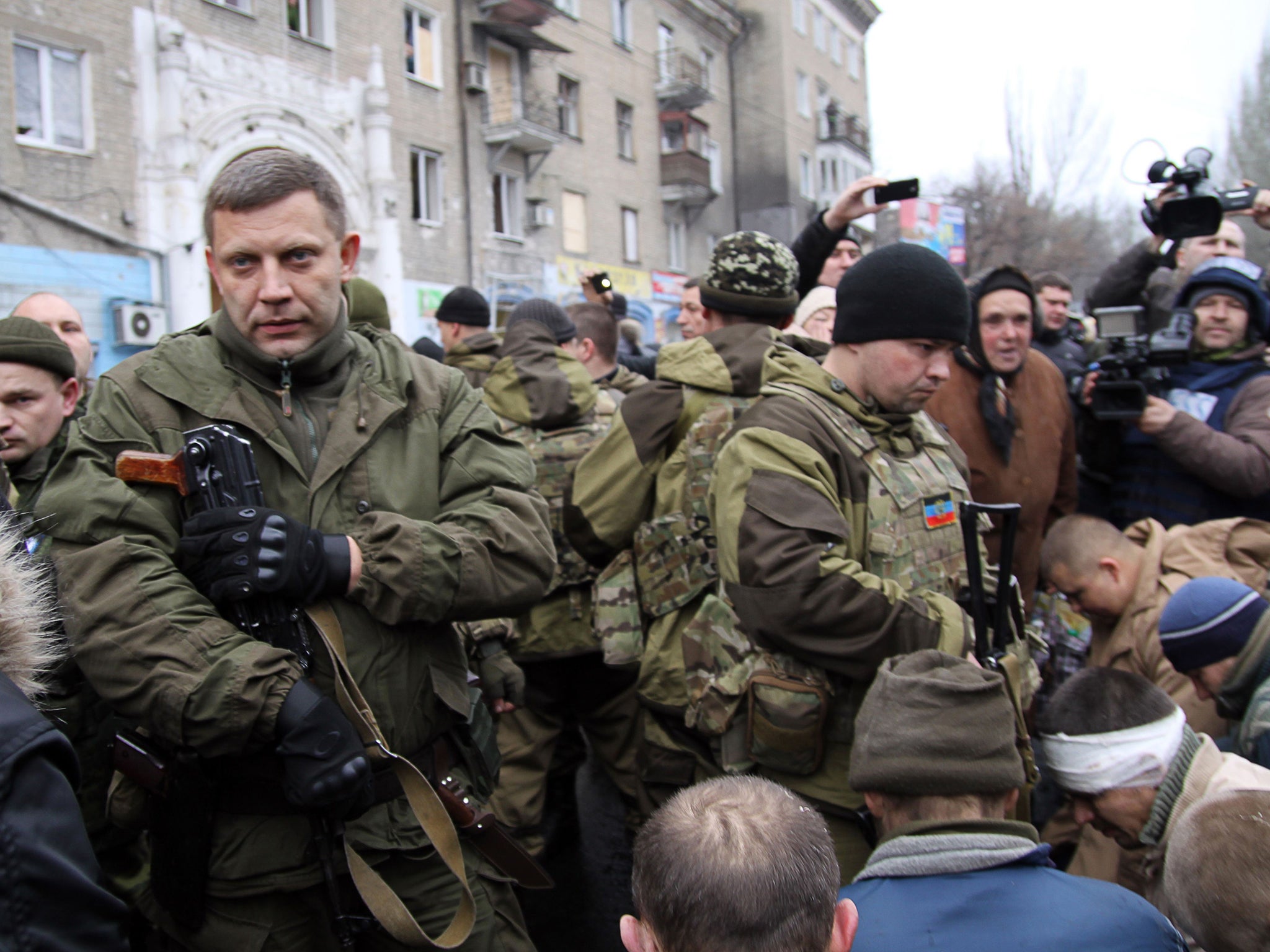 The leader of the self-declared Donetsk People’s Republic Alexander Zakharchenko (on left) next to kneeling captive Ukrainian soldiers at a bus stop where 13 people were killed