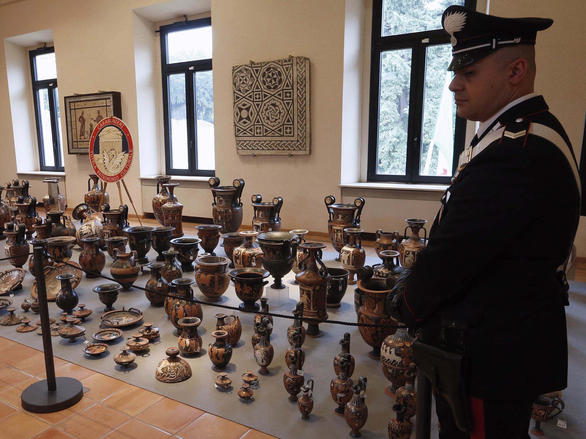A Carabinieri police stands next to rare Greek and Roman amphoras, statues, vases and frescoes