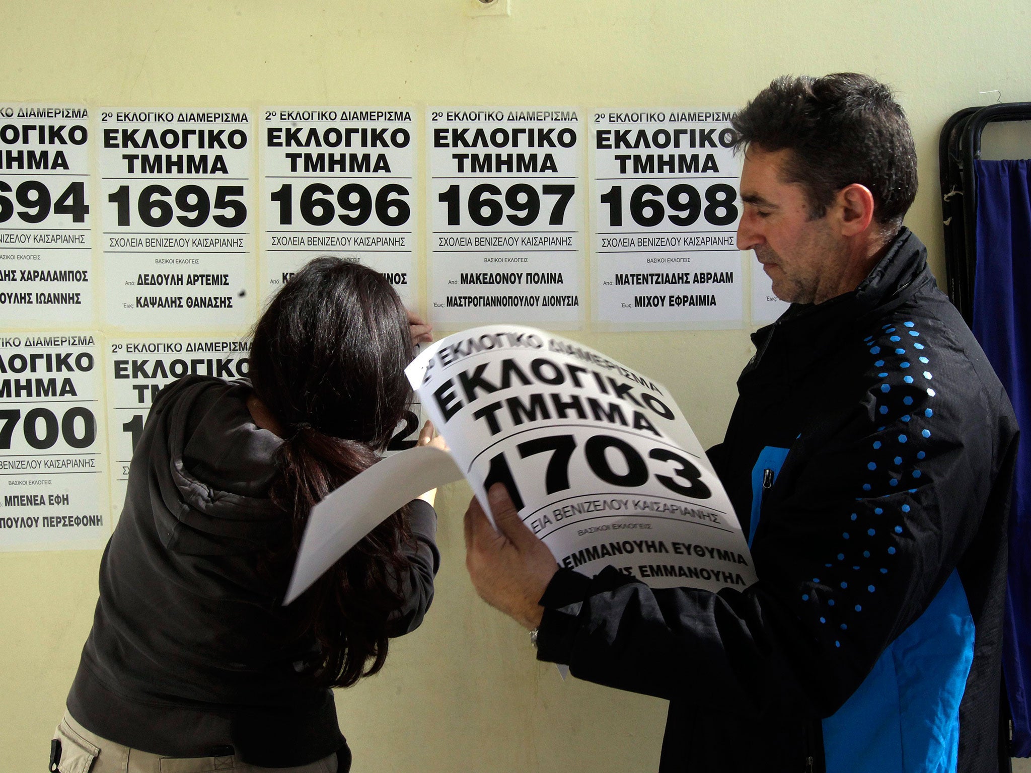 Workers put up signs that indicate the polling stations in a school