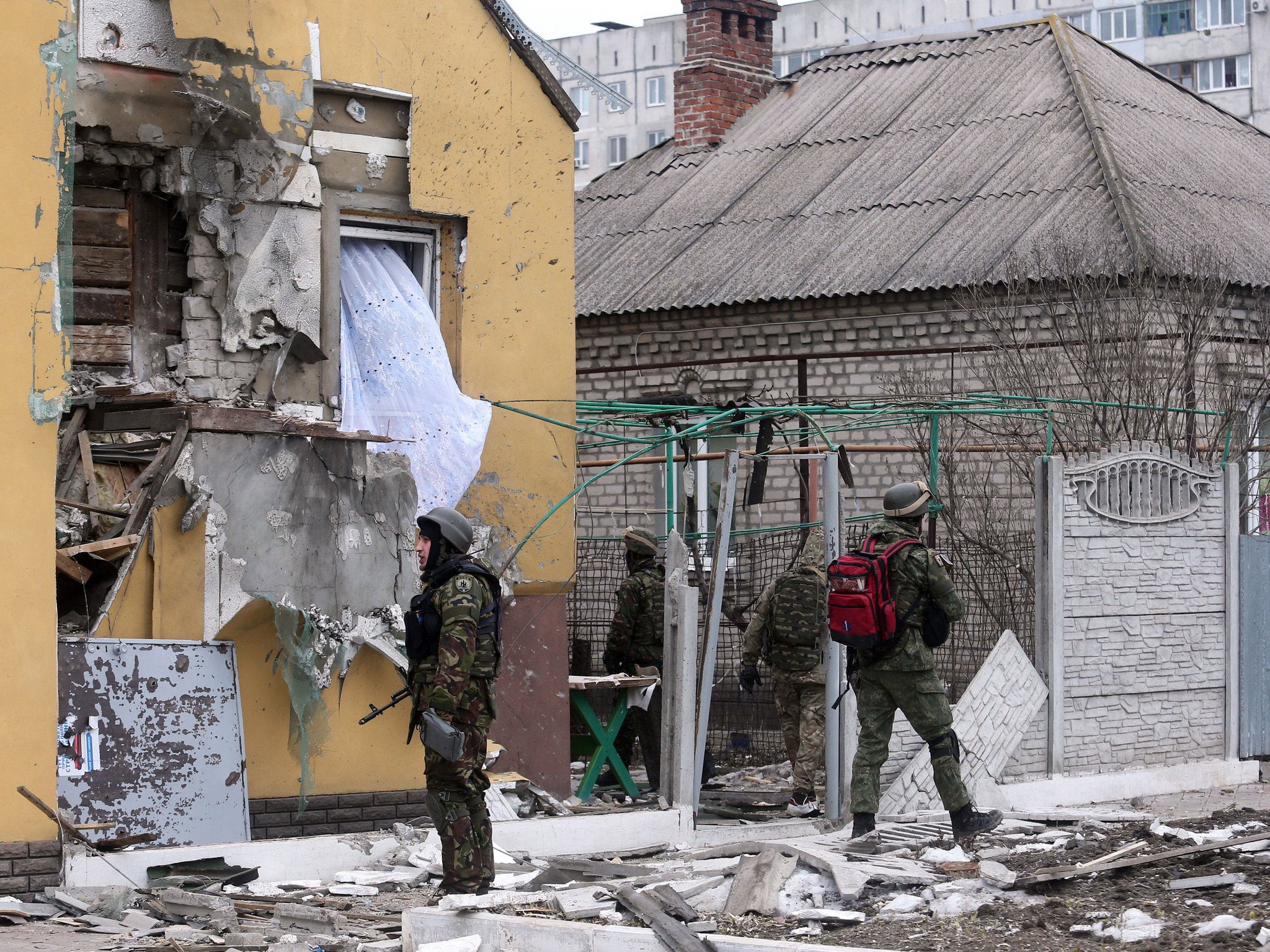 Ukrainian servicemen patrol around a damaged building after shelling in the southern Ukrainian port city of Mariupol on 24, 2015.