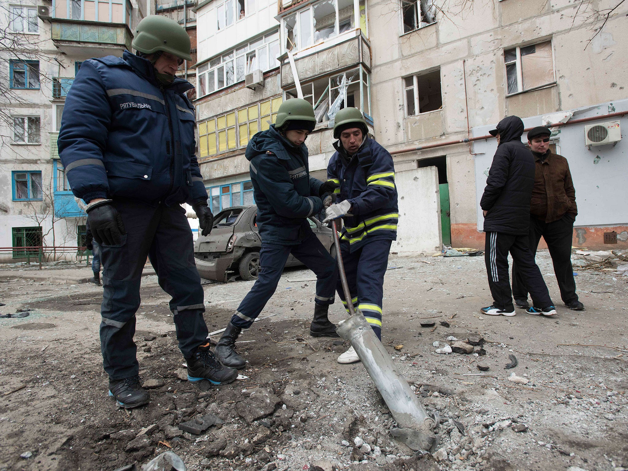 Rescuers retrieve a piece of an exploded Grad missile after the shelling of Mariupol