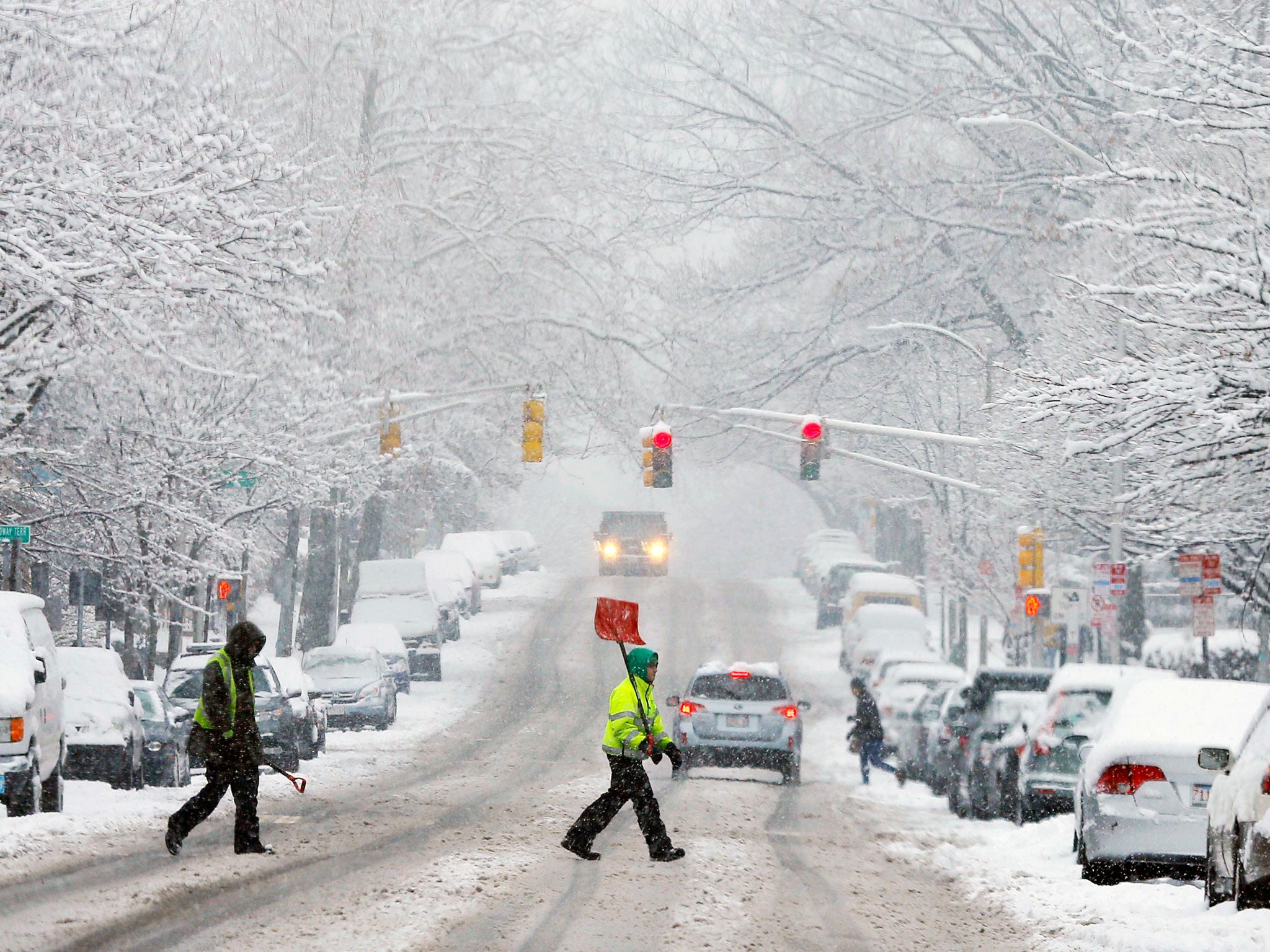 A snow shoveler crosses a street during a winter snowstorm in Cambridge, Massachusetts