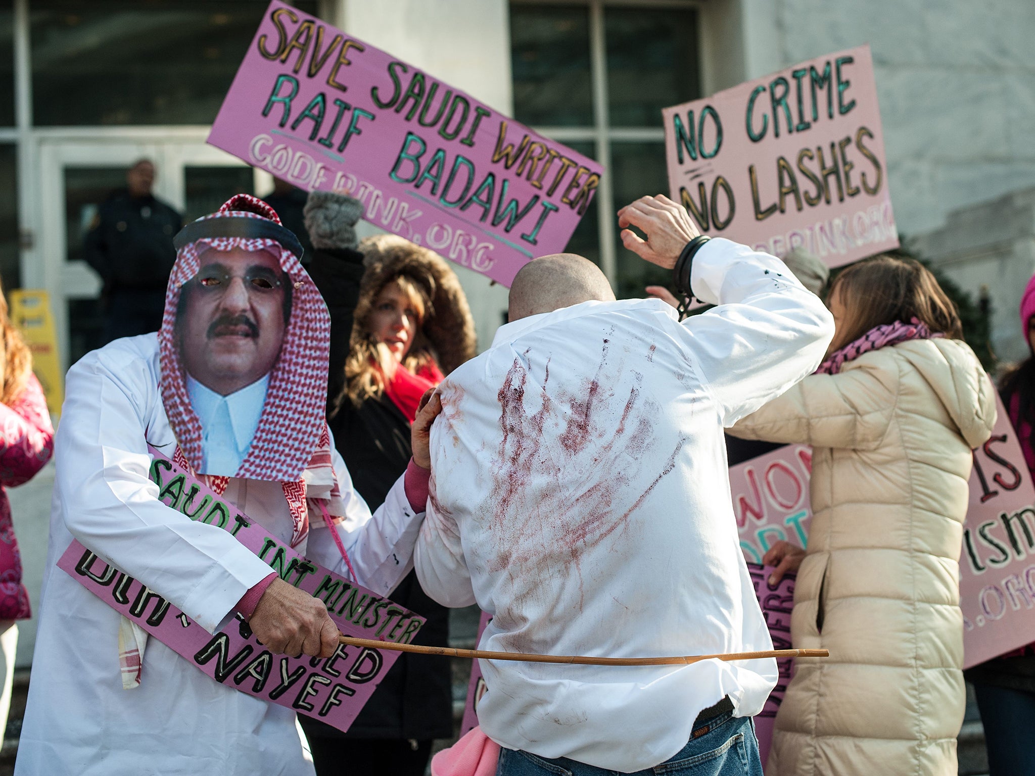 Protesters simulate a flogging in front of the Saudi embassy in Washington DC in protest against the 10-year prison sentence and 1,000 lashes of Saudi activist Raef Badawi (Getty)