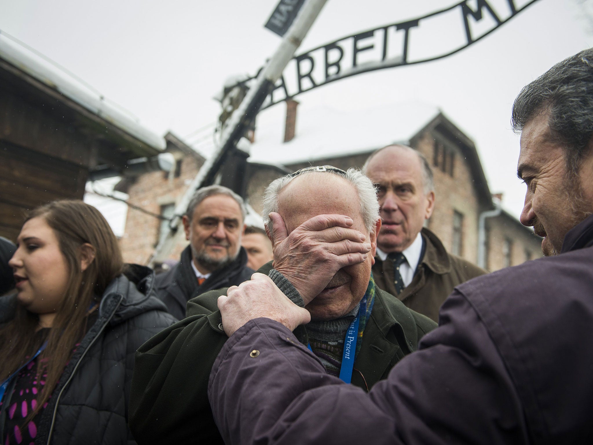 Holocaust survivor Mordechai Ronen (C) from the US is comforted by his son as he is overcome by emotion standing next to President of the World Jewish Congress Ronald Lauder (2nd R) as he arrives at the former Auschwitz concentration camp in Oswiecim on 26 January 2015