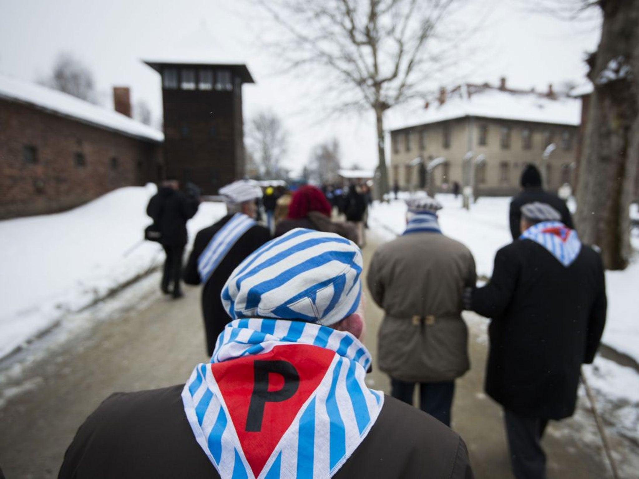 Survivors walk past a watch tower after paying tribute at the "death wall" execution site at Auschwitz on the 70th anniversary of its liberation