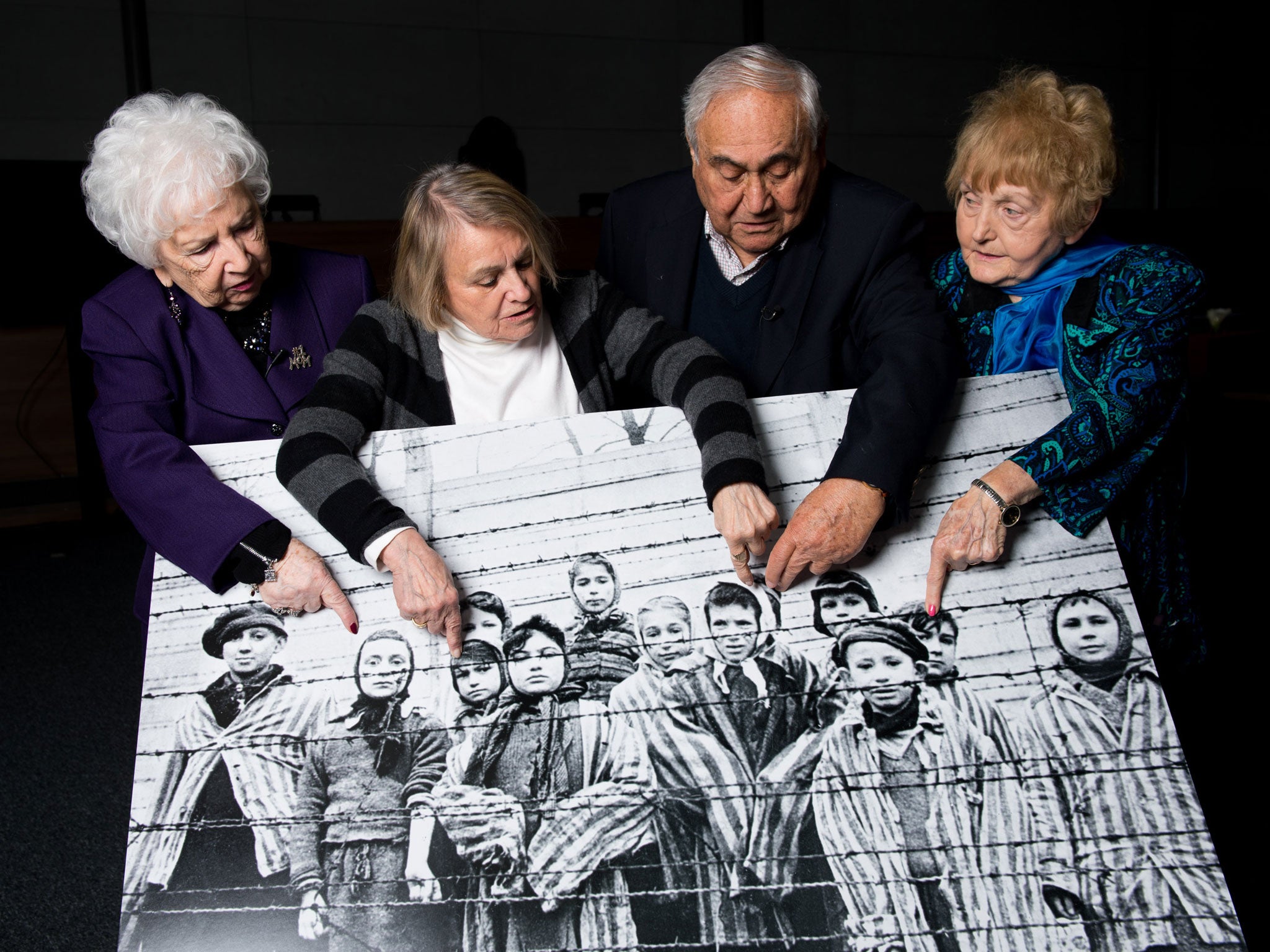79-year-old Miriam Ziegler (left), 81-year-old Paula Lebovics, 85-year-old Gabor Hirsch and 80-year-old Eva Kor pose with the original image of them as children taken at Auschwitz at the time of its liberation on January 26, 2015 in Krakow, Poland.