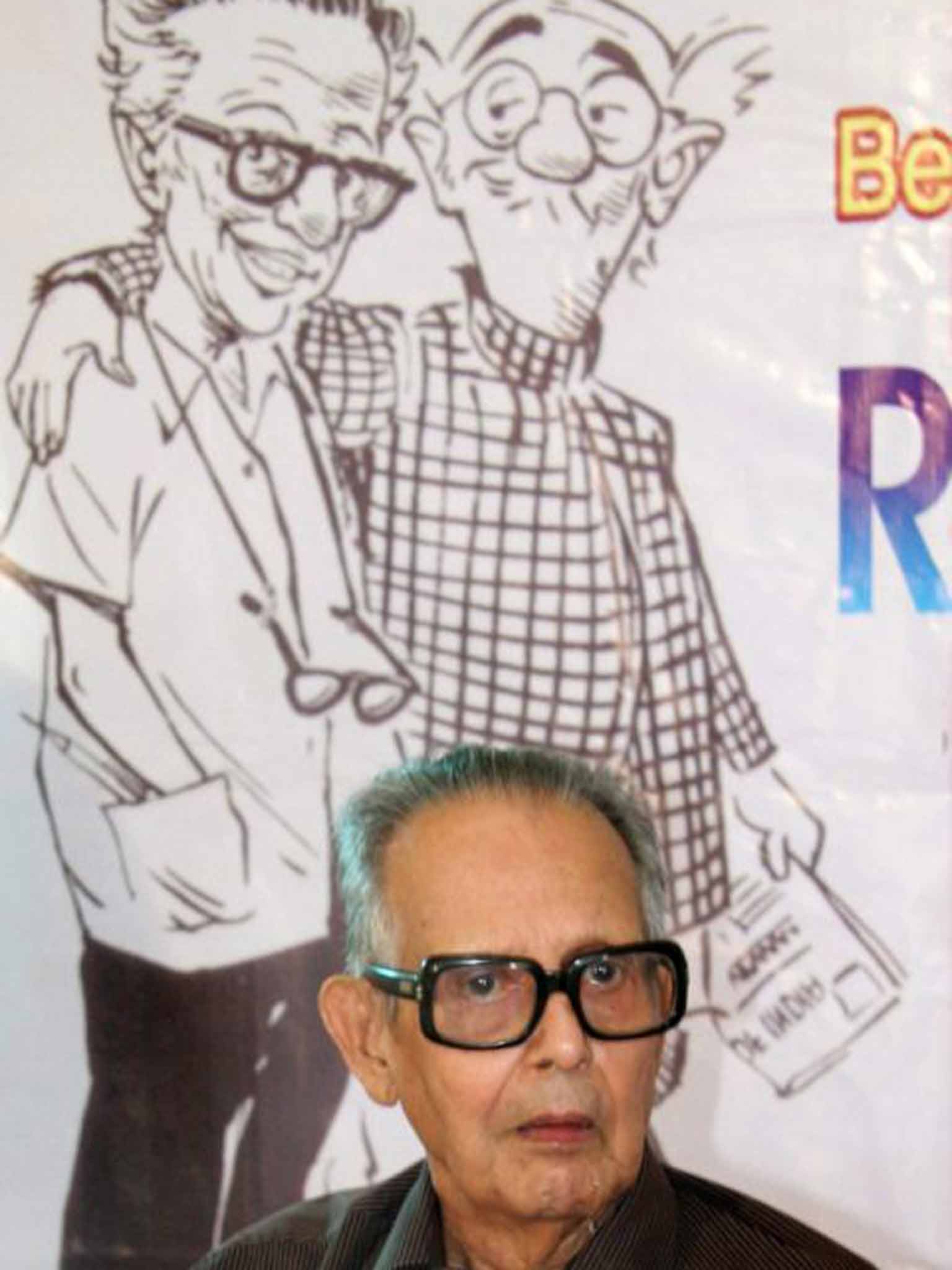 Laxman in front of a depiction of his most famous creation, The Common Man, in the check shirt