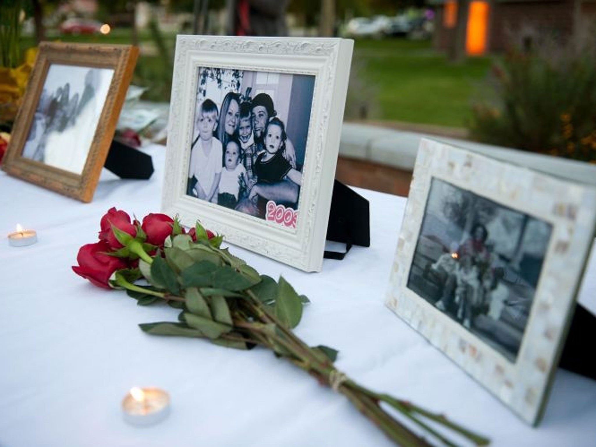 Flowers and photos are on display during a vigil for the Strack family at Pioneer Park in Provo, Utah.