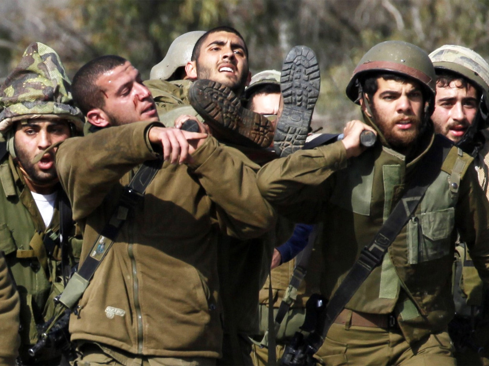 Israeli soldiers carry a casualty after an attack in the Lebanese border area