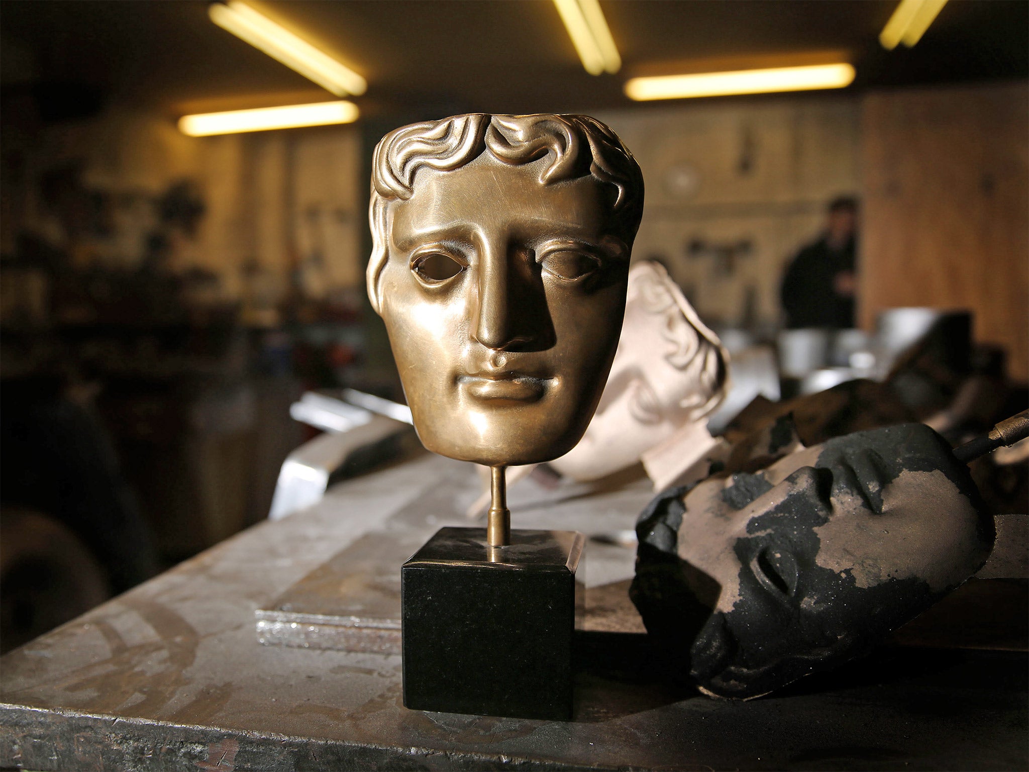 A bronze Bafta mask, created by hand, stands on a workbench at the foundry in West Drayton where they are produced every year (Invision/AP)